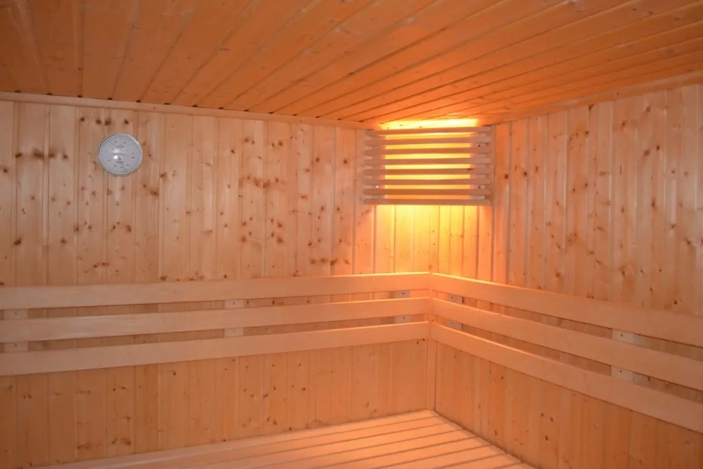 Interior de una sauna de madera clara con luz cálida